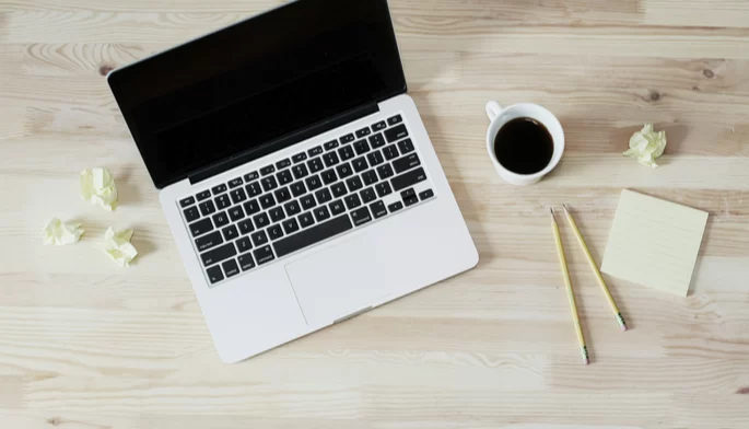 Ein Computer steht auf dem Schreibtisch neben einer Tasse schwarzen Kaffees.